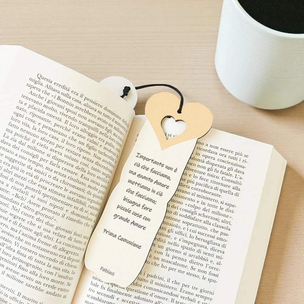 Foto ambientata del segnalibro bomboniera Prima Comunione con calice e ostia, appoggiato su un libro aperto